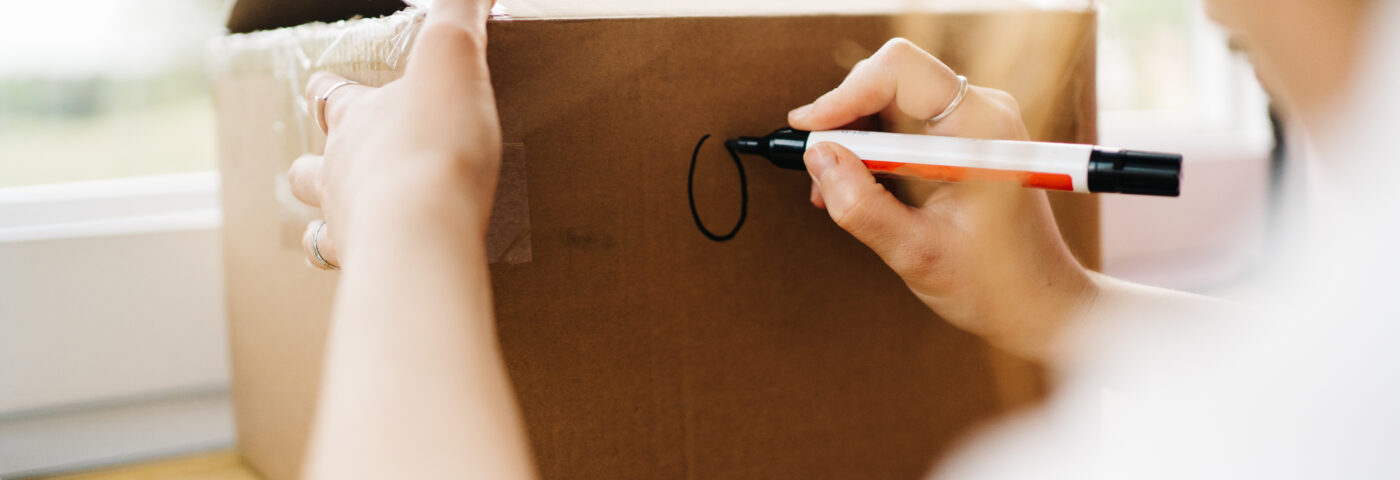 Femme écrivant sur une boîte de déménagement
