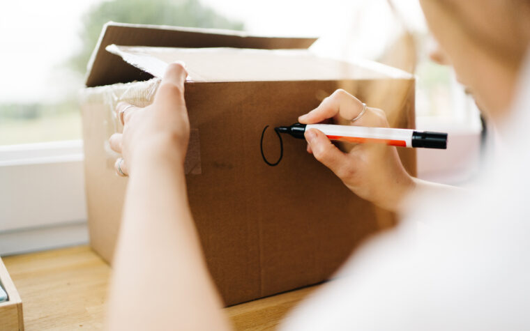 Femme écrivant sur une boîte de déménagement