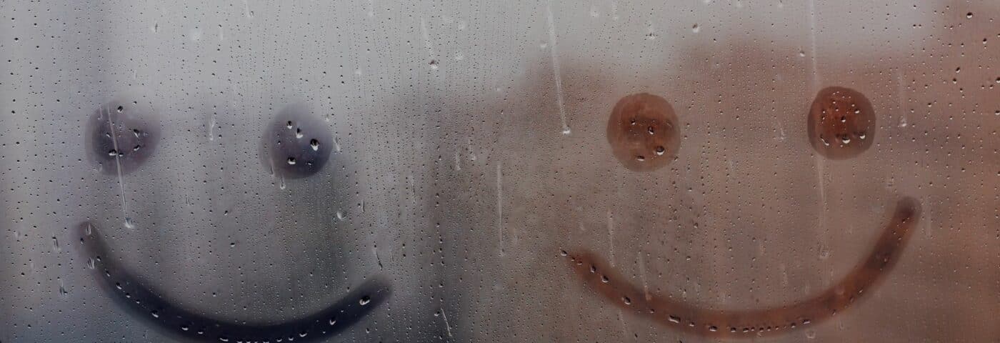 Smileys dessinés dans une fenêtre avec condensation