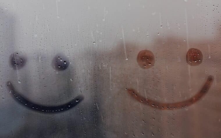 Smileys dessinés dans une fenêtre avec condensation